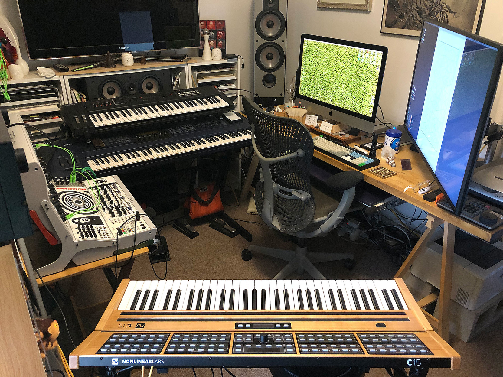 Various synthesizers and computer monitors, arranged in a five-sided ring.
