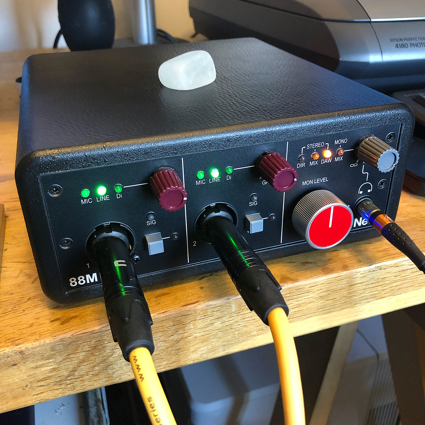 The Neve 88M stereo preamp is a little black box with blinky lights and colorful knobs.

Signal and headphone cables are plugged into the front. 

