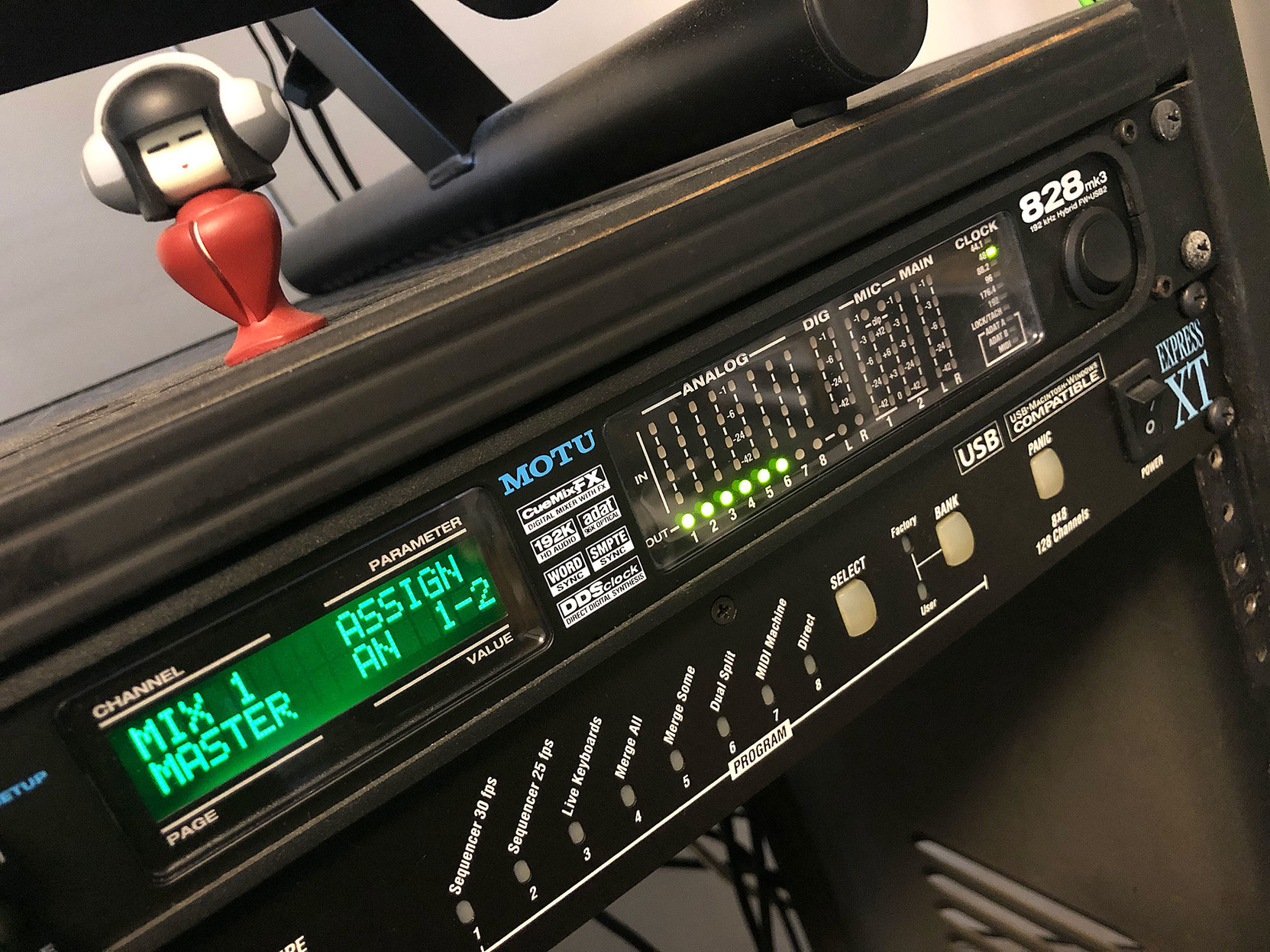 The MOTU audio interface is rack-mounted, with a digital readout and six bright lights showing that a surround signal is passing through in its way to the speakers.