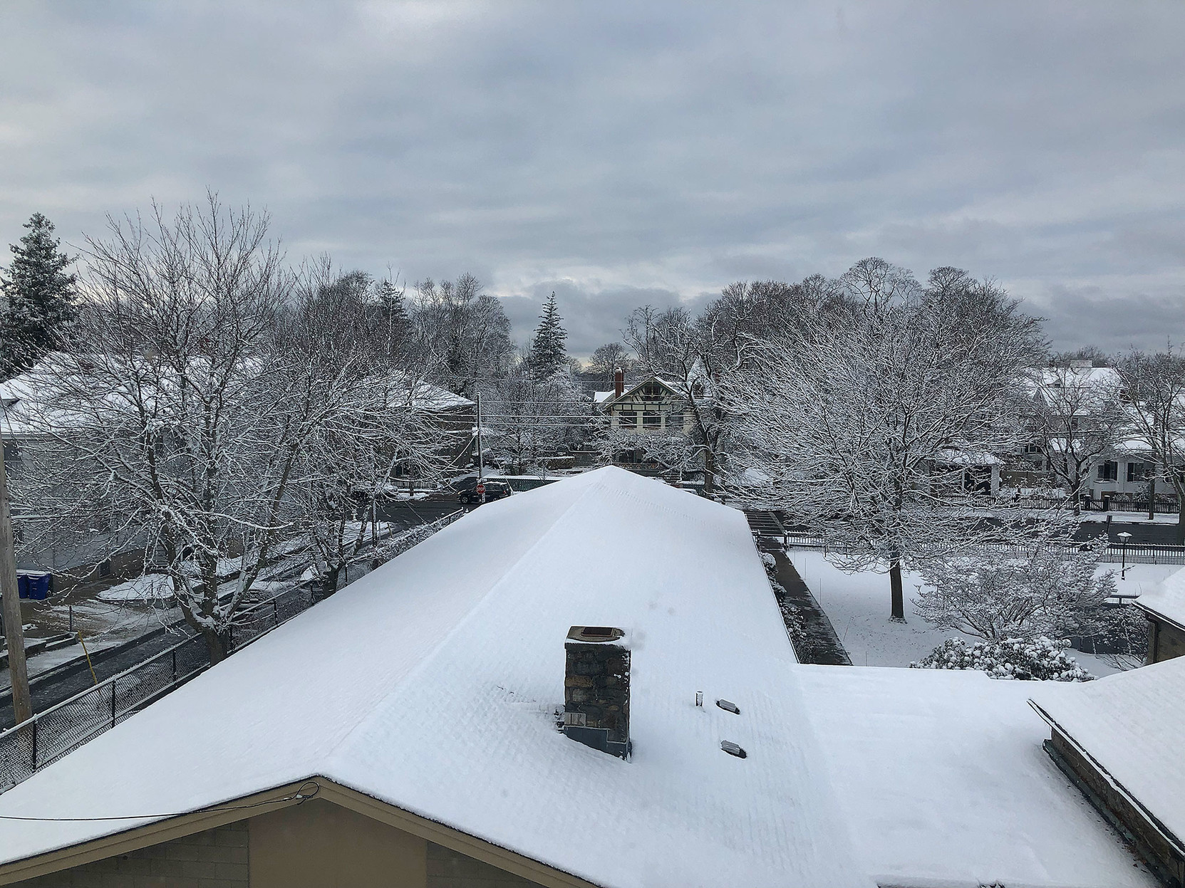 A clouded sky, a roof covered in snow, and trees laced with white.

In the middle distance, there’s a pale yellow house with interesting woodwork on the front …
