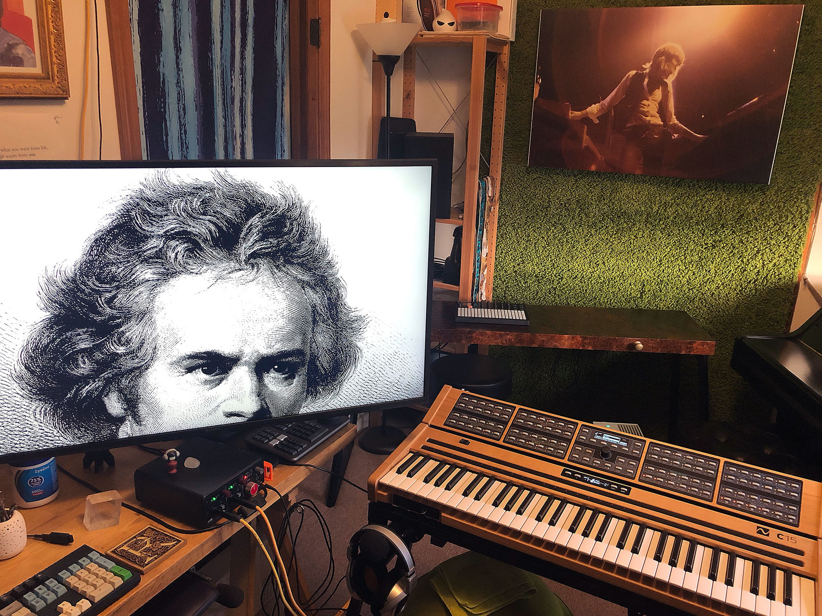 A huge image of Beethoven’s head appears on a large computer monitor, seemingly peering at a C15 synthesizer in the foreground.

In the background, an image of Keith Emerson playing two keyboards at once.