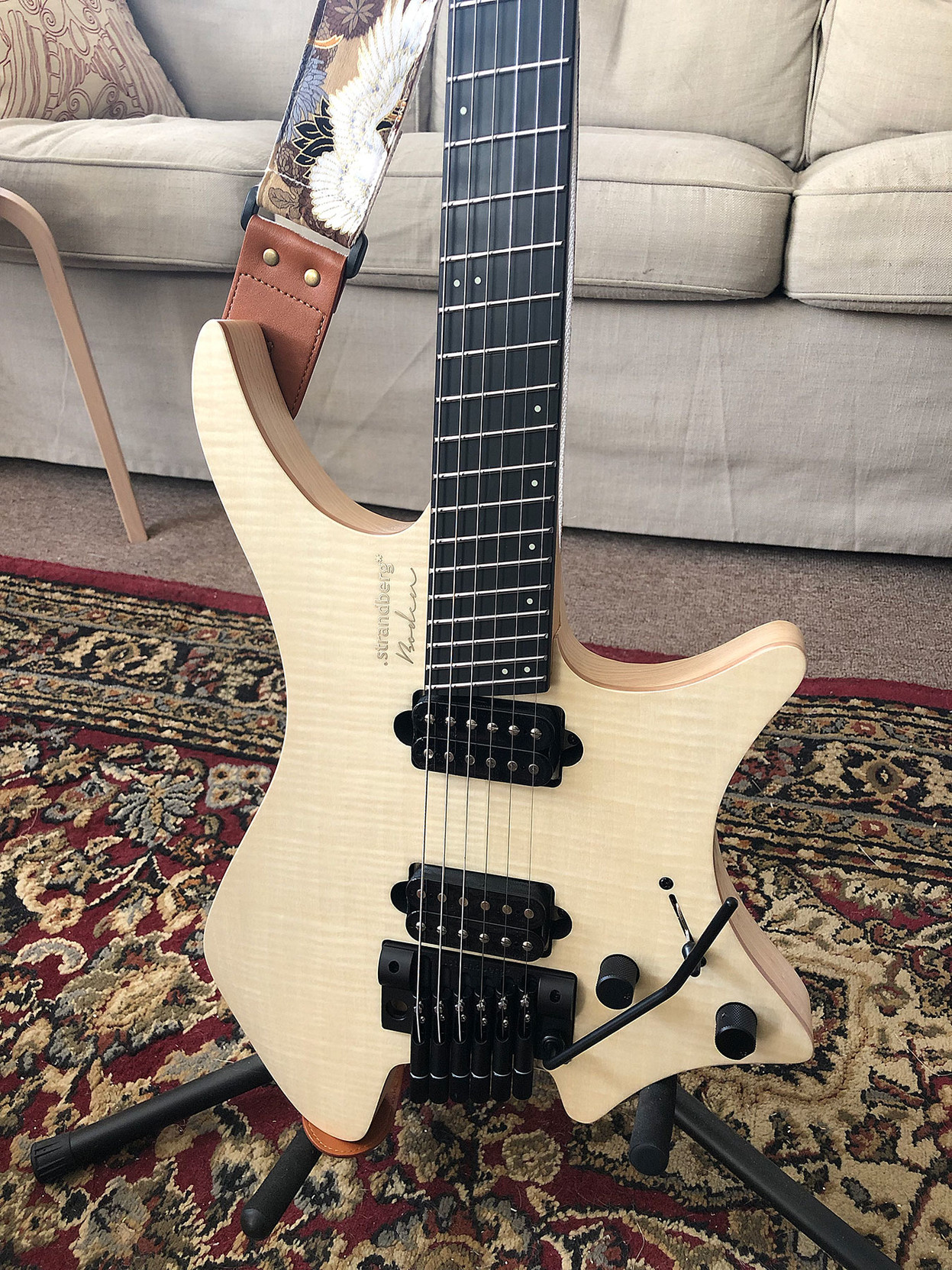 A .strandberg* guitar has a unique shape, with scallops formes on the side and bottom that let you hold it at different angles on your knee.

This one has a natural wood-toned flame maple front. 