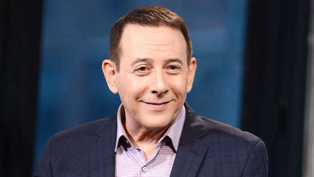 A mature Paul Reubens, looking dapper in a jacket and open-collared shirt.