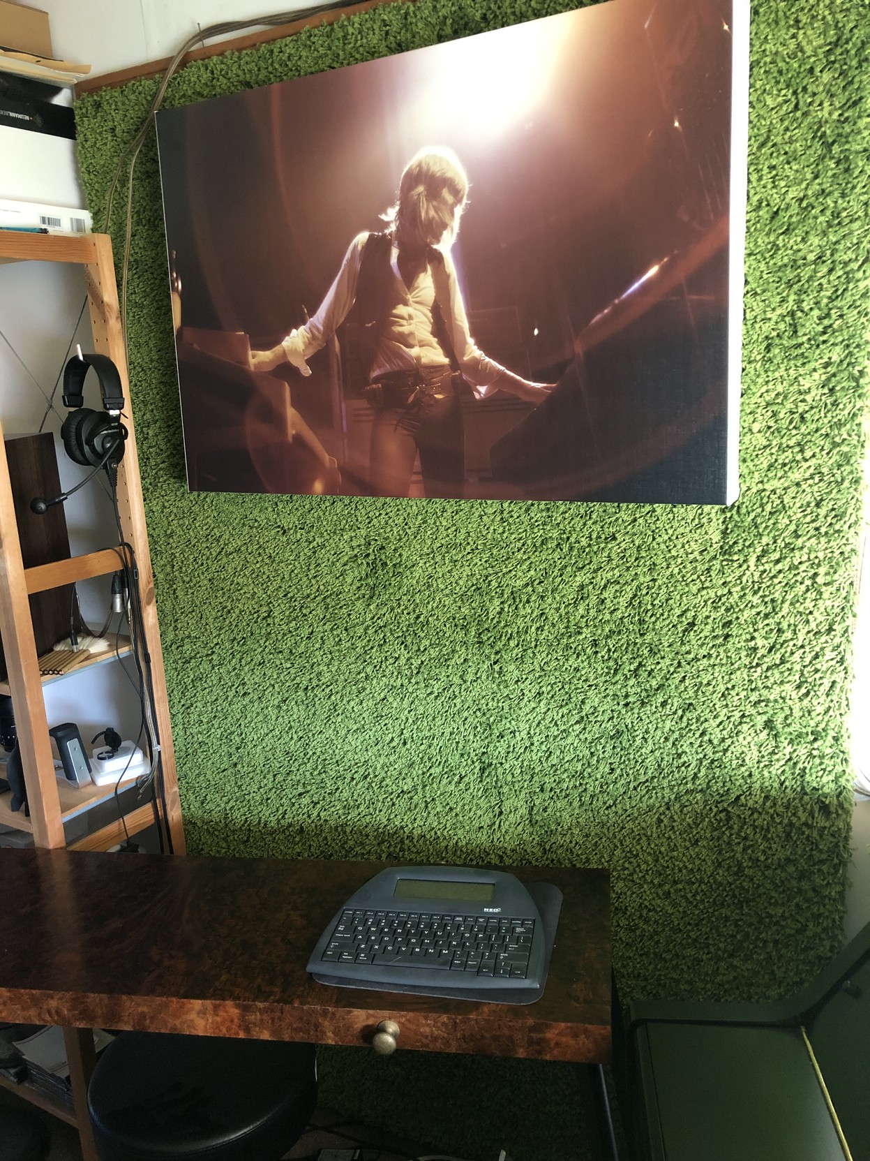 A poster of Keith Emerson playing two keyboards, hanging in front of a green Ikea grass-rug.
