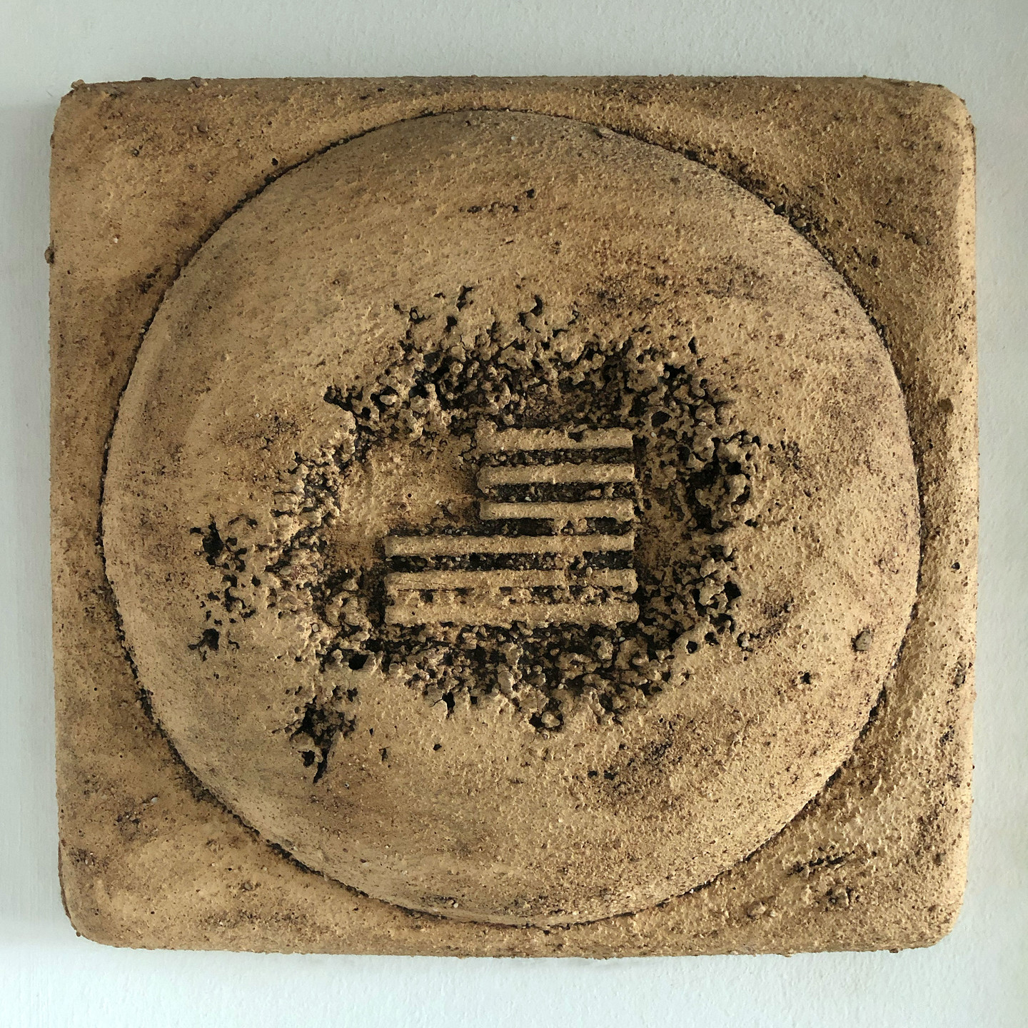 Ceramic sculpture with a stylized American flag revealed in a cratered surface.