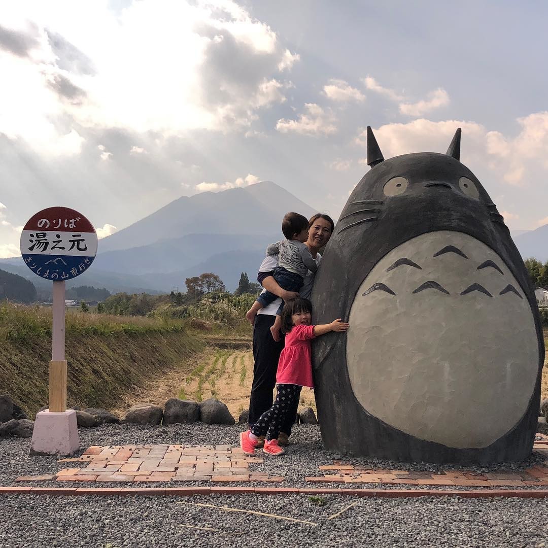 A lucky kid embracing a life-size Totoro sculpture.
