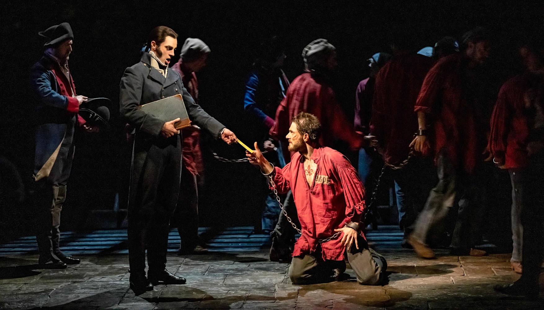 Javert confronting a chained and kneeling Jean Valjean.