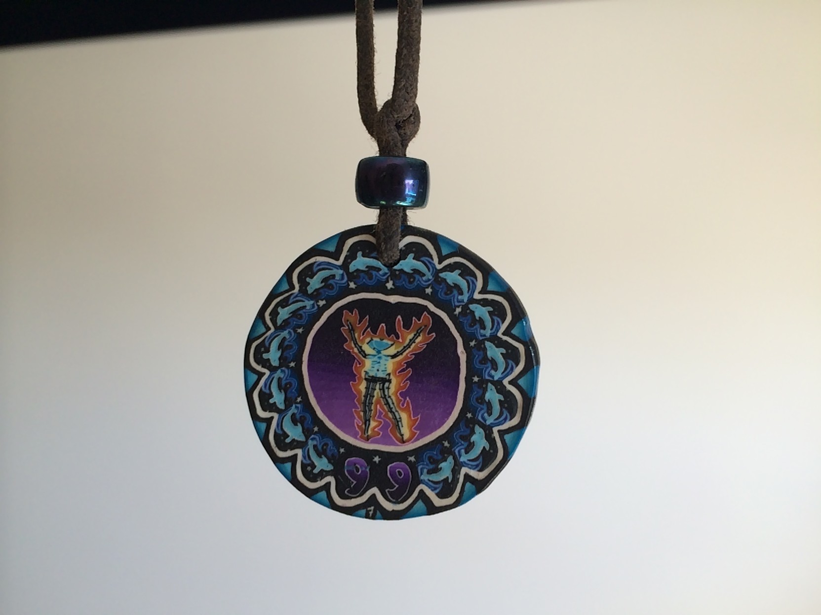 This pendant was hung around my neck by an unknown woman, while I was playing solo synthesizer live at Burning Man. 

I didn’t realize what she had done until after I had finished, when someone looked at me and said “Hey man, you got tagged!”

It depicts the eponymous Burning Man in flames, surrounded by a ring of leaping dolphins. It’s beautiful work, and I wish I could have thanked her for it.