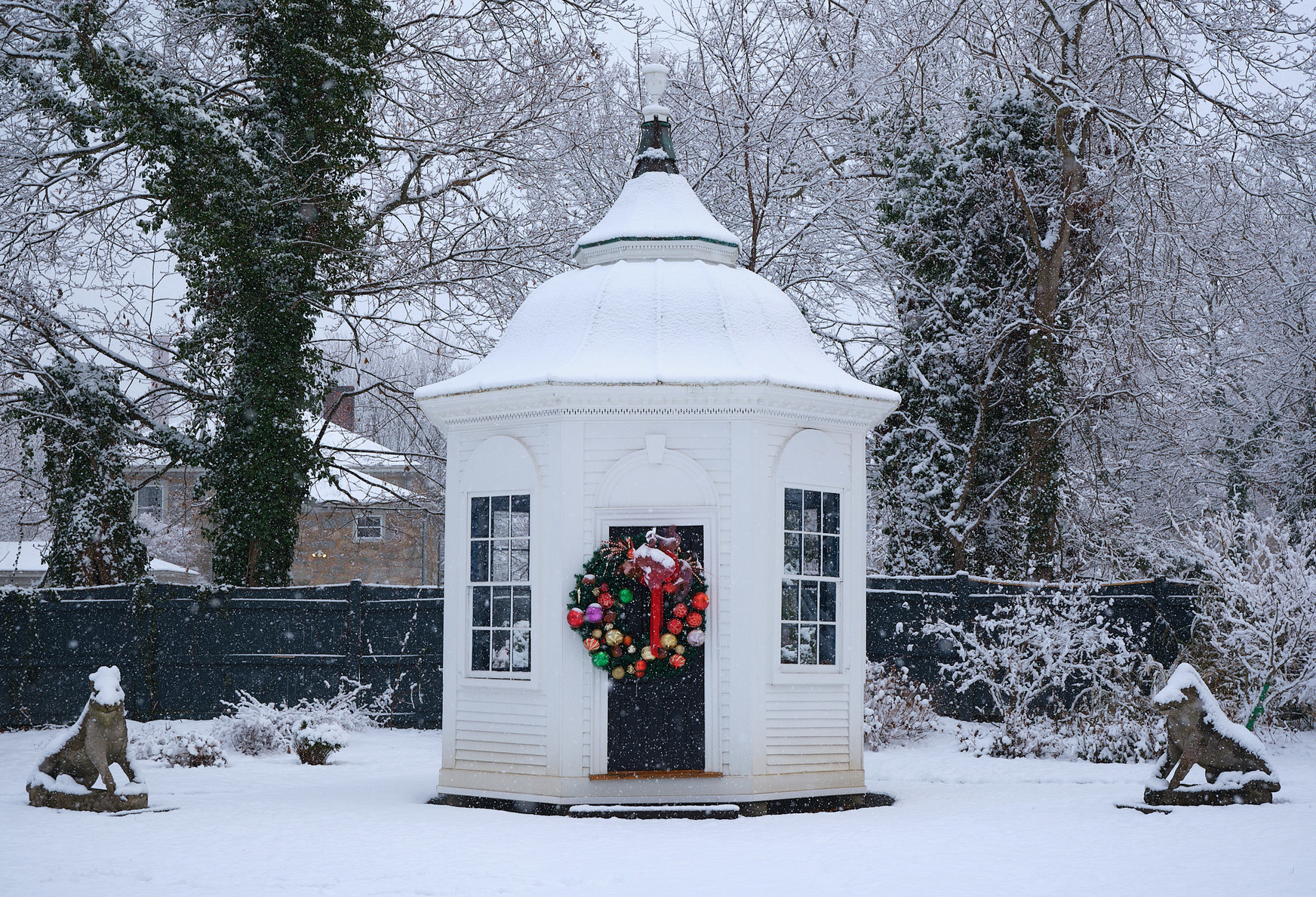 A little white cupola, with a wreath of ornaments on its door.
