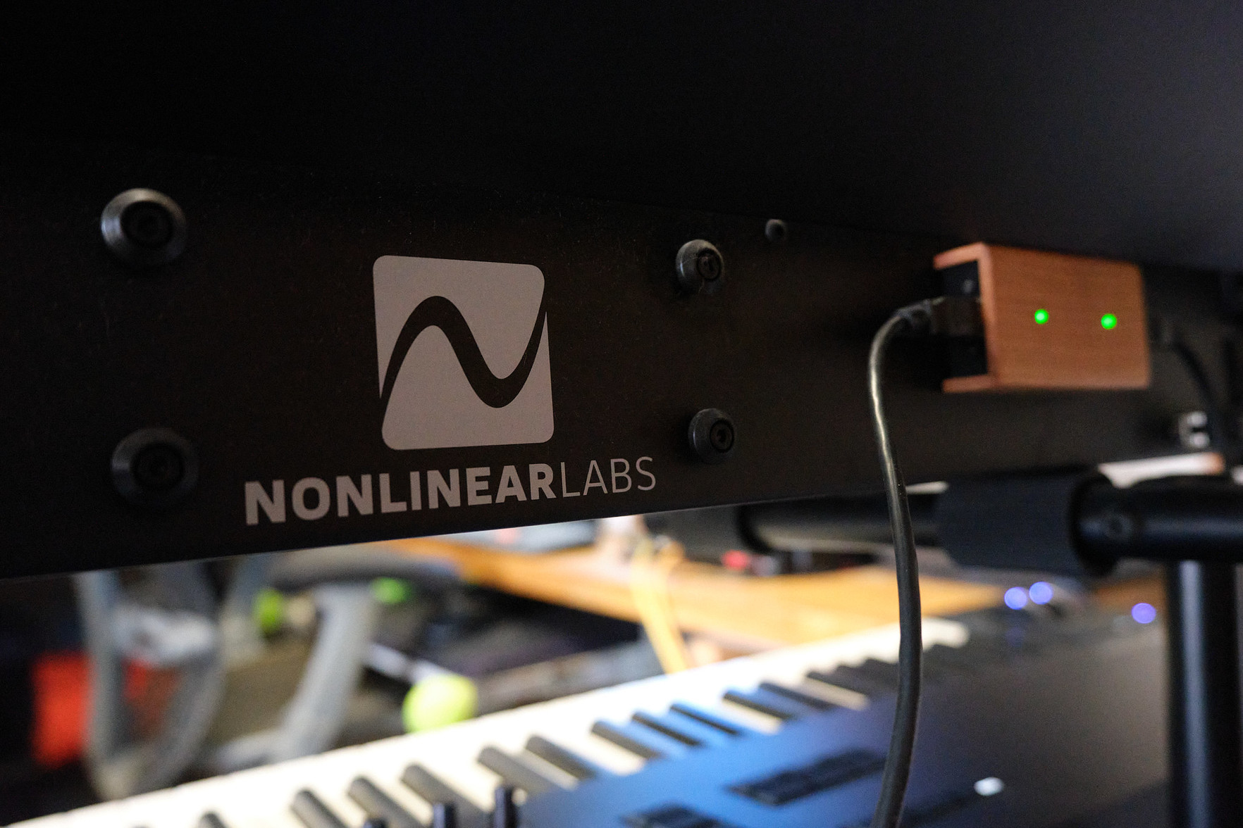 Shot from the rear of the C15, showing the Nonlinear Labs logo and two green glowing LEDs on the MIDI Bridge.