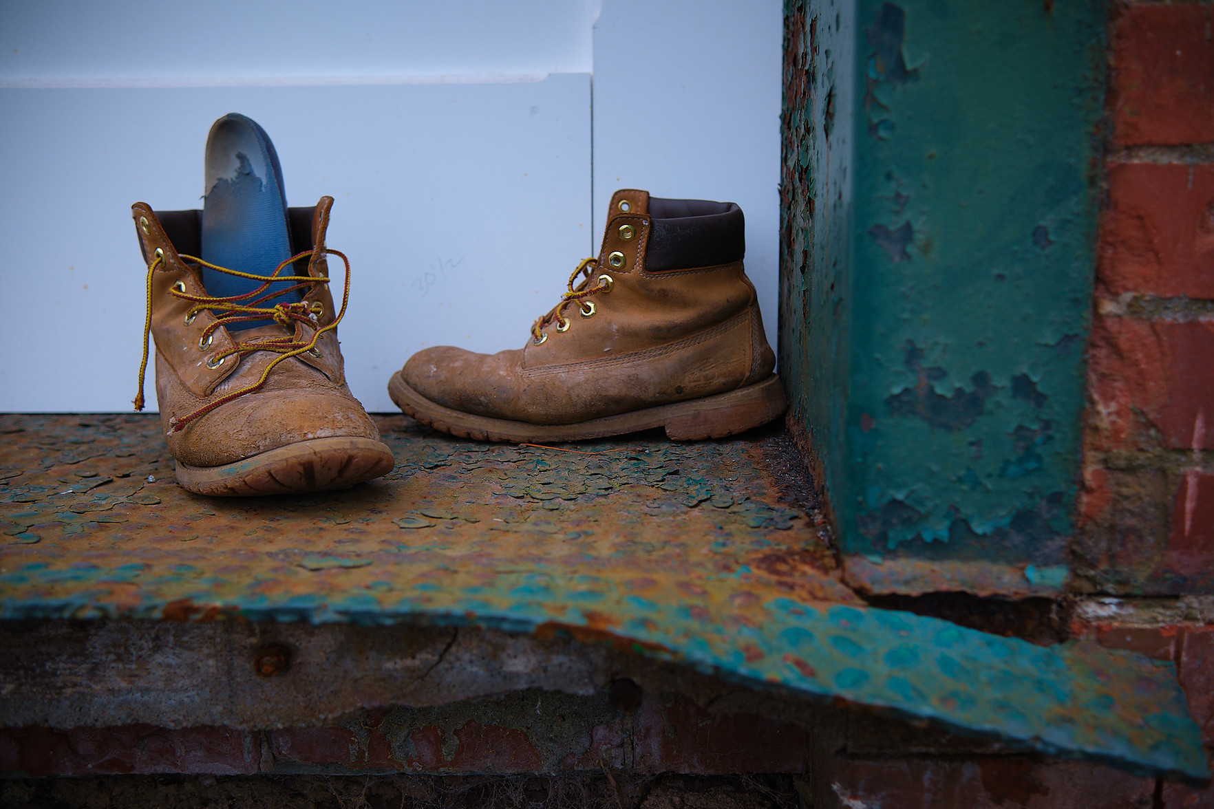 A pair of seemingly abandoned boots by a building undergoing renovation.